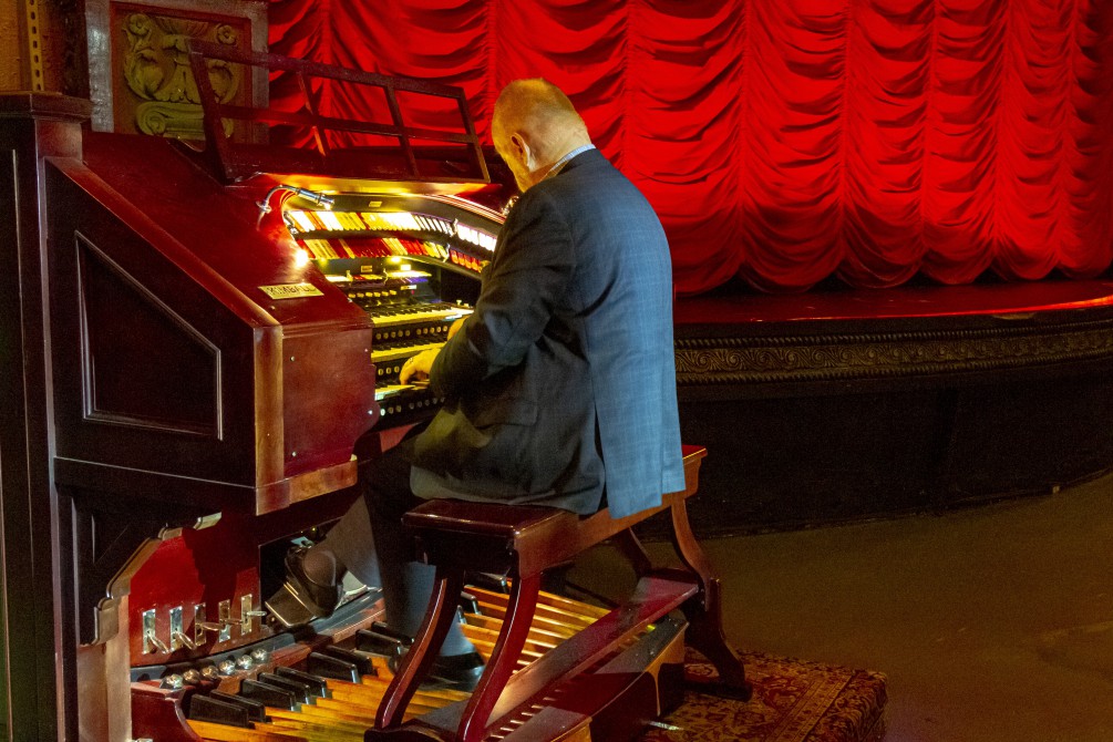 Dennis Scott playing the Music Box Organ with the red waterfall curtain in the background.